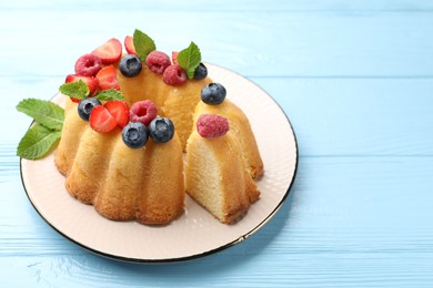 Photo of Tasty Bundt cake with berries and mint on light blue wooden table, closeup. Space for text