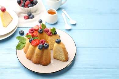 Photo of Tasty Bundt cake with berries, honey and mint on light blue wooden table, closeup. Space for text