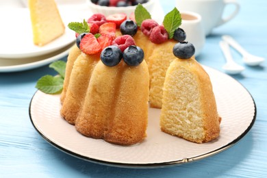 Photo of Tasty Bundt cake with berries and mint on light blue wooden table, closeup