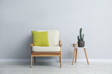 Photo of Comfortable armchair and decor near light gray wall indoors