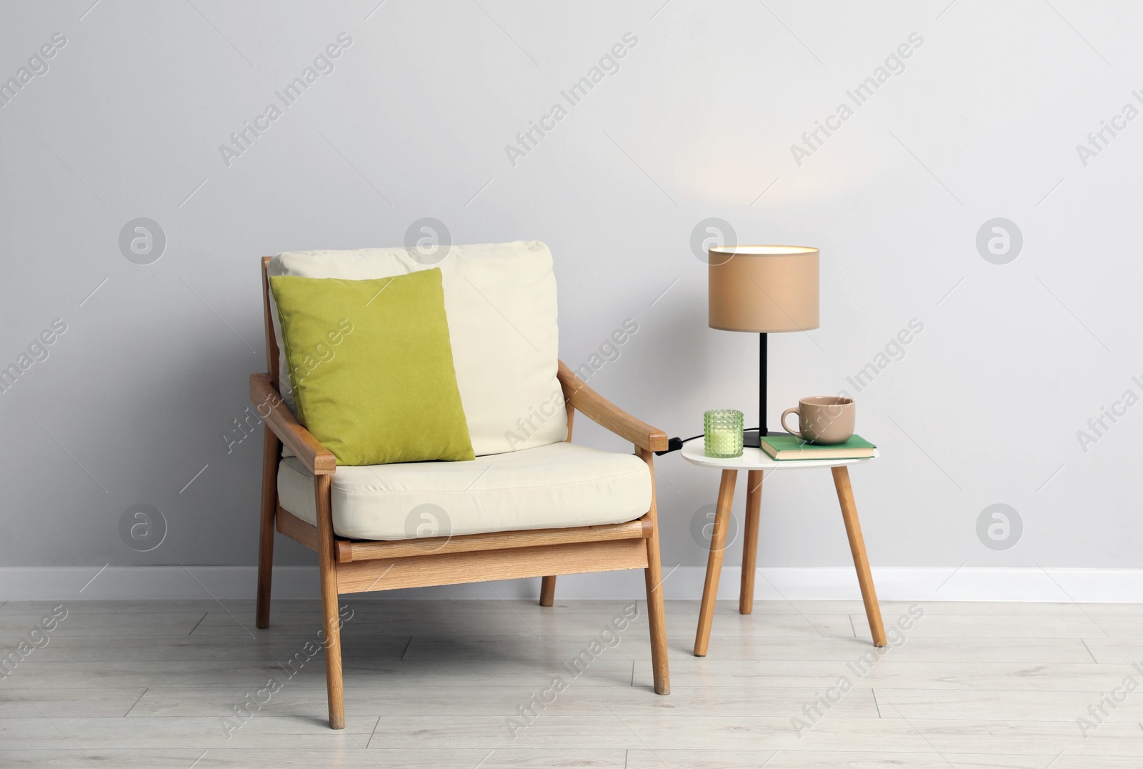 Comfortable armchair and decor near light gray wall indoors Photo of Comfortable armchair and decor near light gray wall indoors