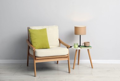 Photo of Comfortable armchair and decor near light gray wall indoors