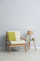 Photo of Comfortable armchair and decor near light gray wall indoors