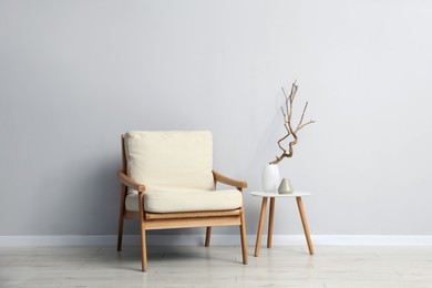 Photo of Comfortable armchair and decor near light gray wall indoors