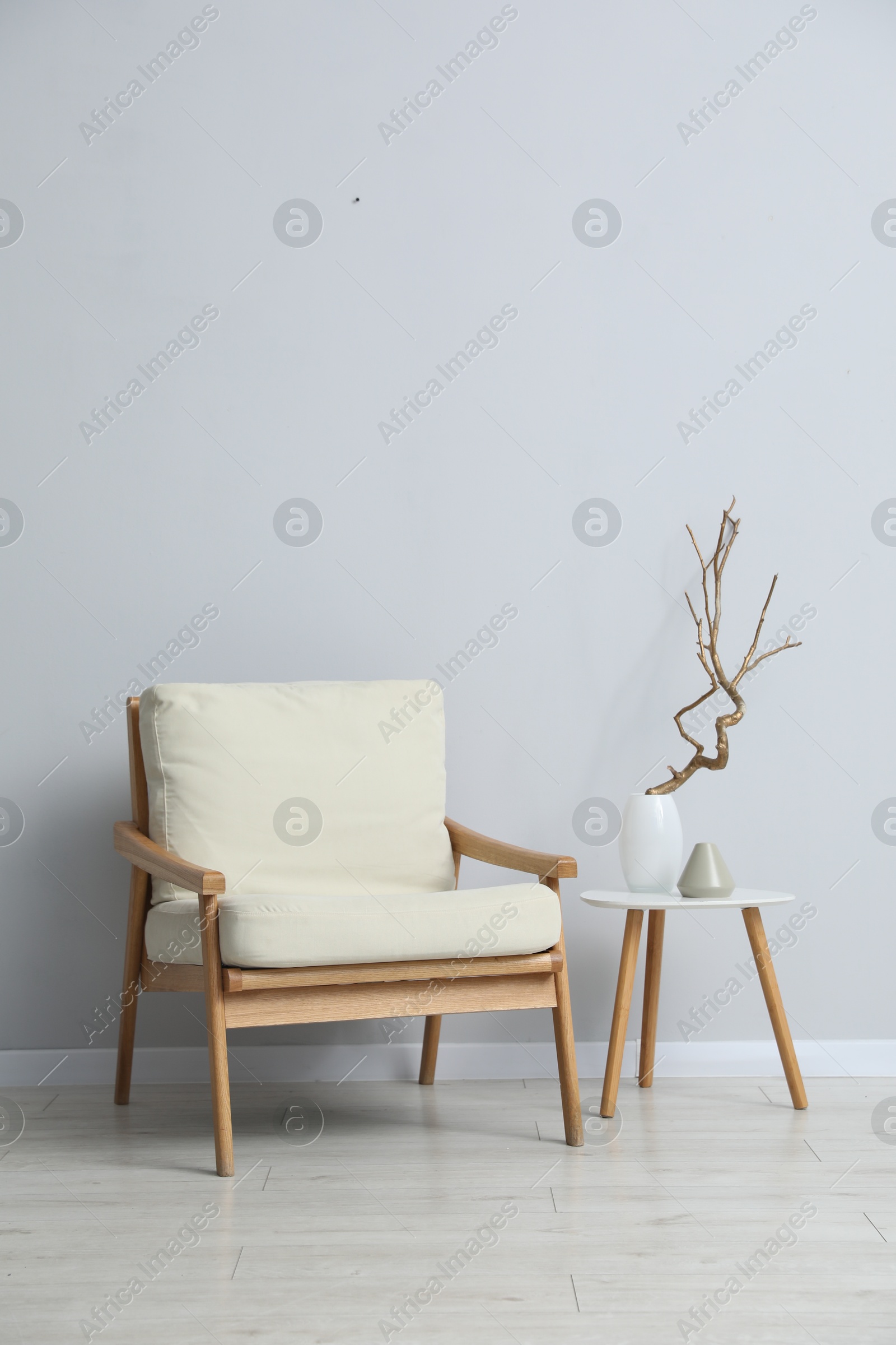 Comfortable armchair and decor near light gray wall indoors Photo of Comfortable armchair and decor near light gray wall indoors