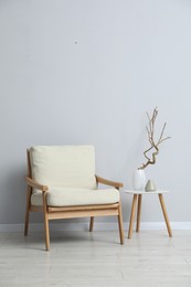 Photo of Comfortable armchair and decor near light gray wall indoors