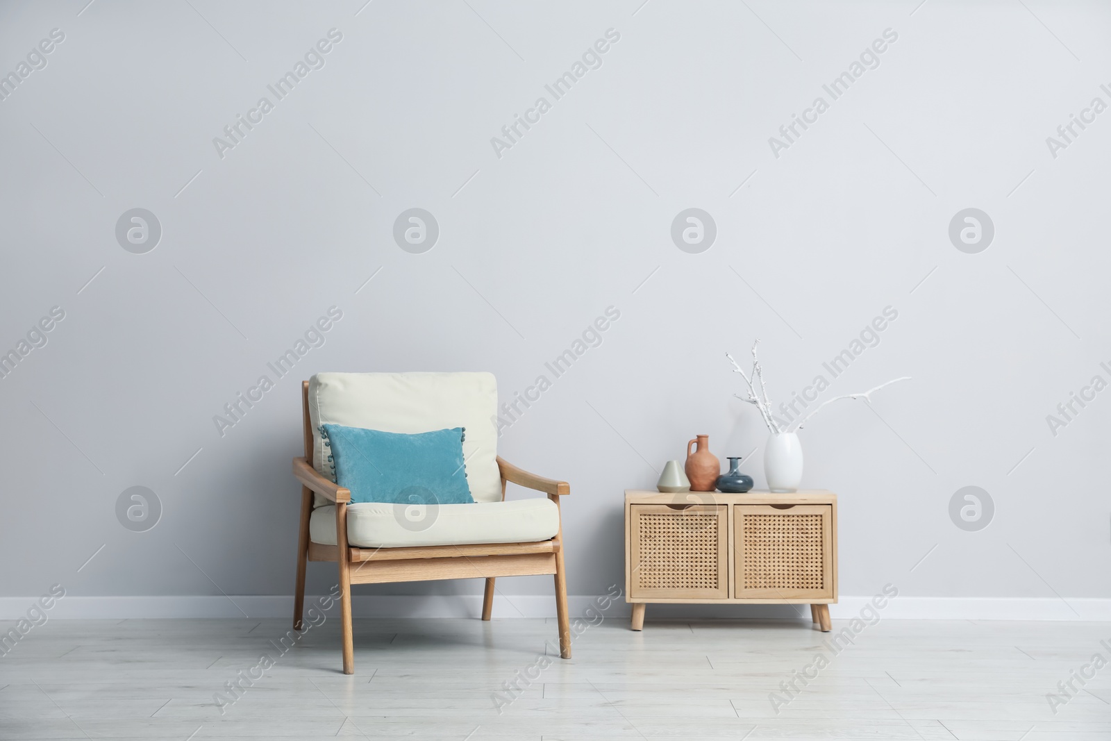 Comfortable armchair and decor near light gray wall indoors Photo of Comfortable armchair and decor near light gray wall indoors