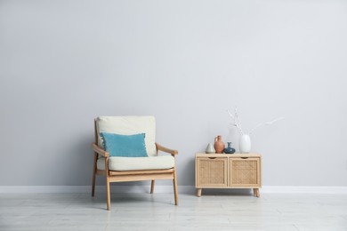Photo of Comfortable armchair and decor near light gray wall indoors