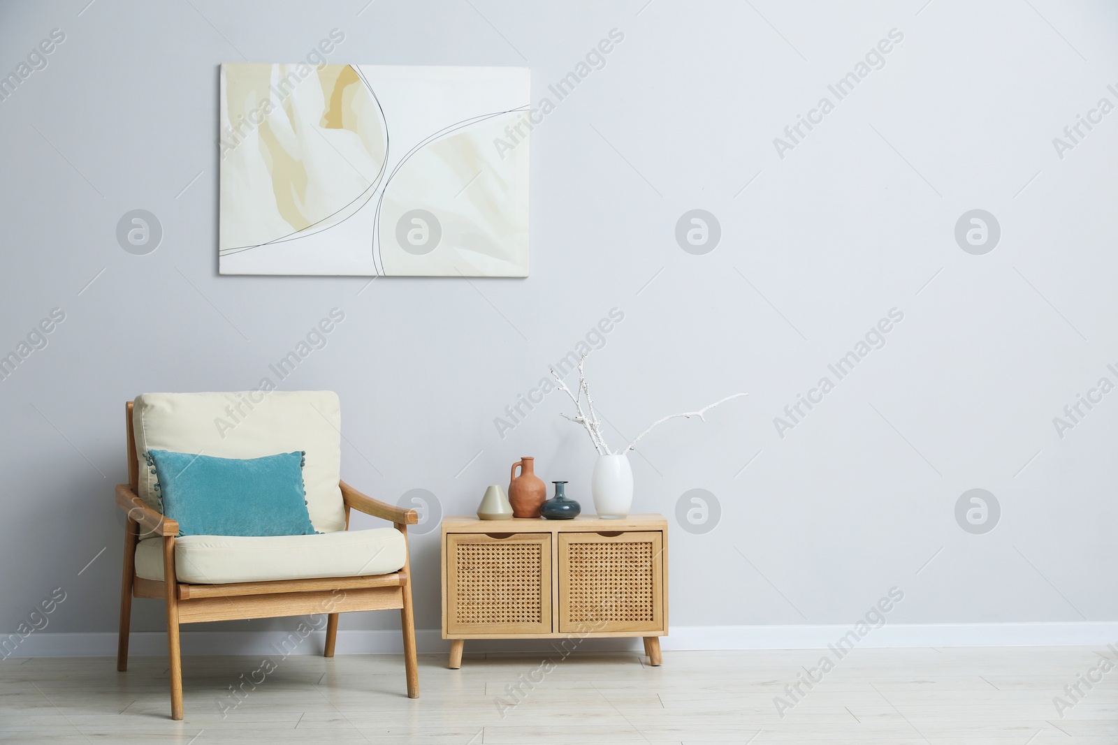 Comfortable armchair and decor near light gray wall indoors. Space for text Photo of Comfortable armchair and decor near light gray wall indoors. Space for text