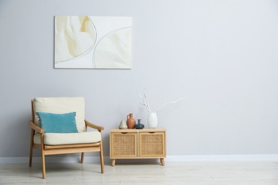 Photo of Comfortable armchair and decor near light gray wall indoors. Space for text