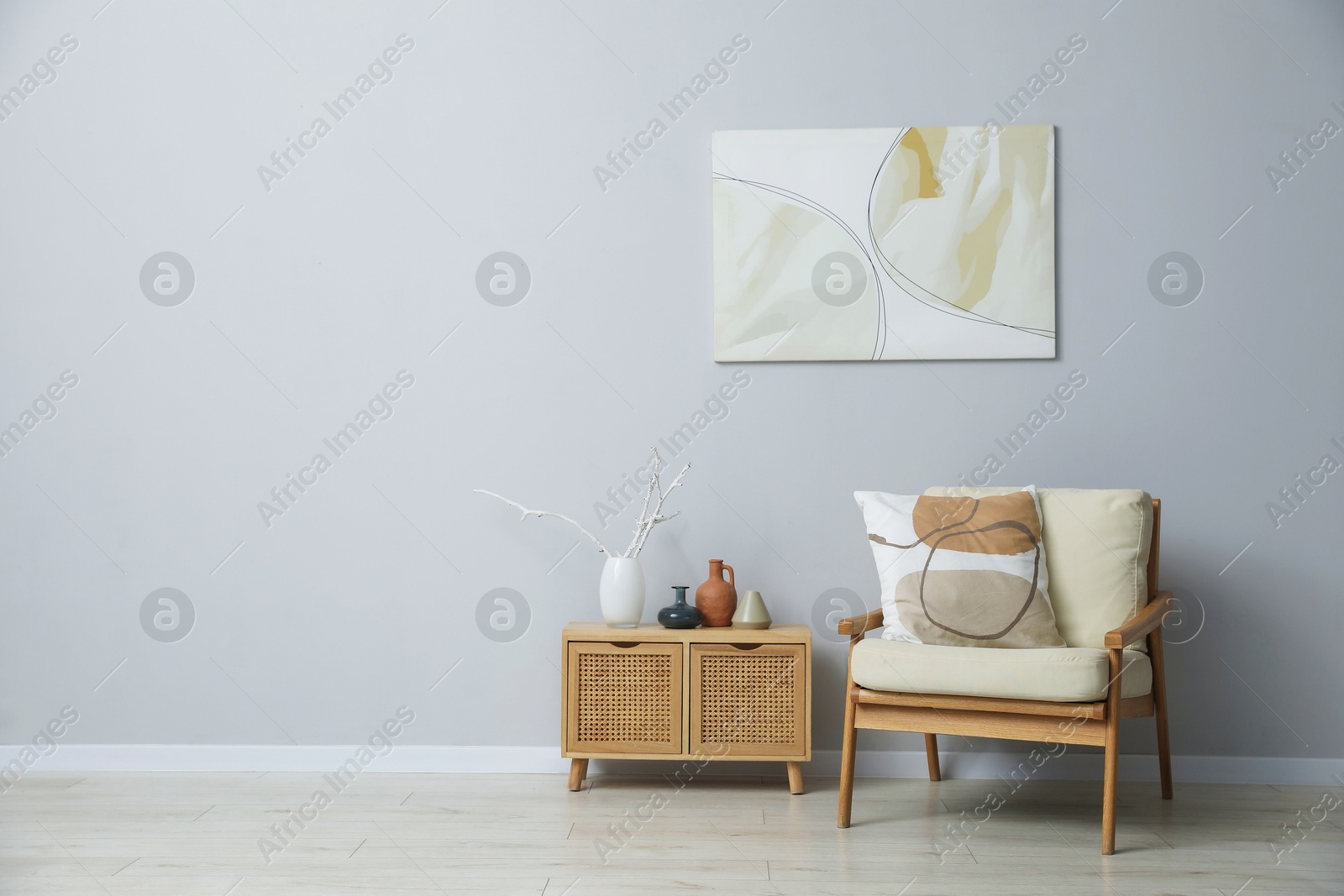 Comfortable armchair and decor near light gray wall indoors. Space for text Photo of Comfortable armchair and decor near light gray wall indoors. Space for text