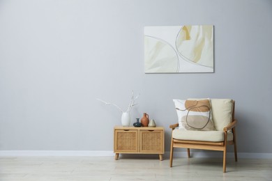 Photo of Comfortable armchair and decor near light gray wall indoors. Space for text