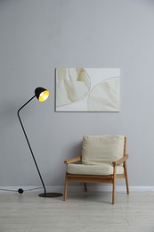 Photo of Comfortable armchair and lamp near light gray wall indoors