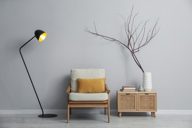 Photo of Comfortable armchair and decor near light gray wall indoors