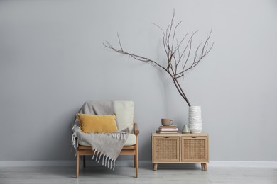 Photo of Comfortable armchair and decor near light gray wall indoors