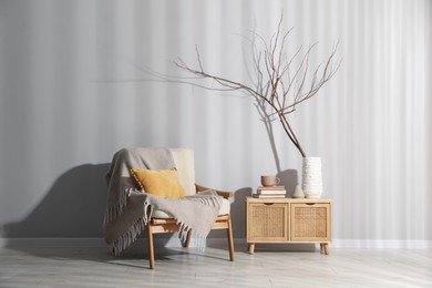Photo of Comfortable armchair and decor near light gray wall indoors