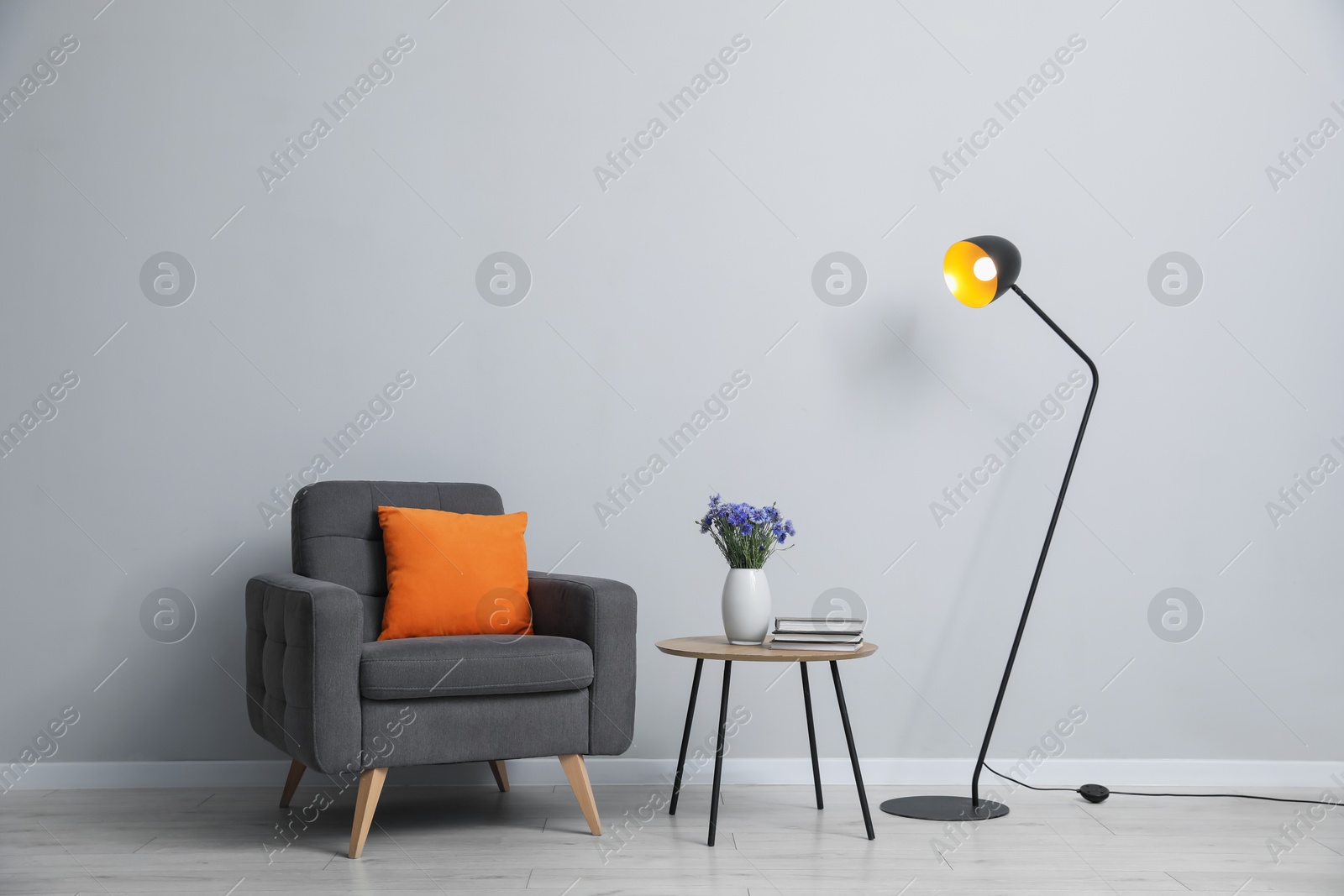 Comfortable armchair and decor near light gray wall indoors Photo of Comfortable armchair and decor near light gray wall indoors