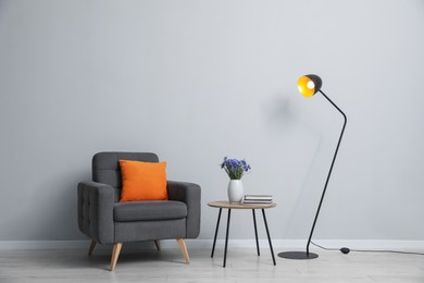 Photo of Comfortable armchair and decor near light gray wall indoors