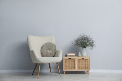 Photo of Comfortable armchair and decor near light gray wall indoors