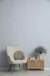 Photo of Comfortable armchair and decor near light gray wall indoors