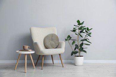 Photo of Comfortable armchair and decor near light gray wall indoors