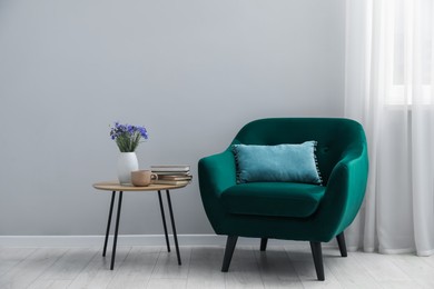 Photo of Comfortable armchair and decor near light gray wall indoors