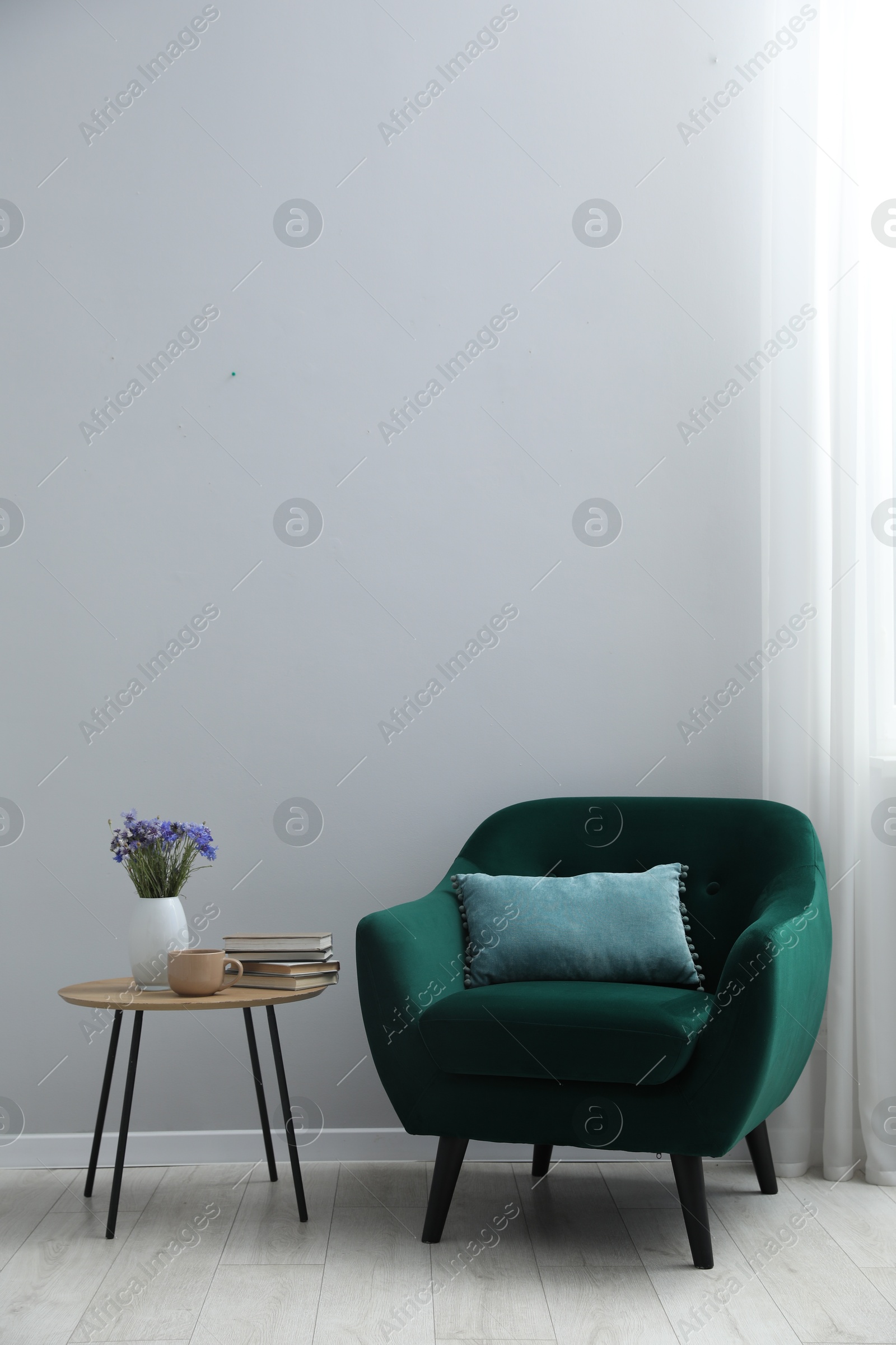 Photo of Comfortable armchair and decor near light gray wall indoors