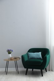 Photo of Comfortable armchair and decor near light gray wall indoors