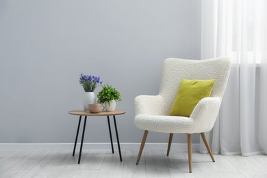 Photo of Comfortable armchair and decor near light gray wall indoors