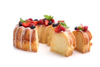 Photo of Pieces of delicious bundt cake with berries, glaze and mint isolated on white