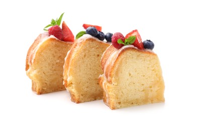 Photo of Pieces of delicious bundt cake with berries, glaze and mint isolated on white
