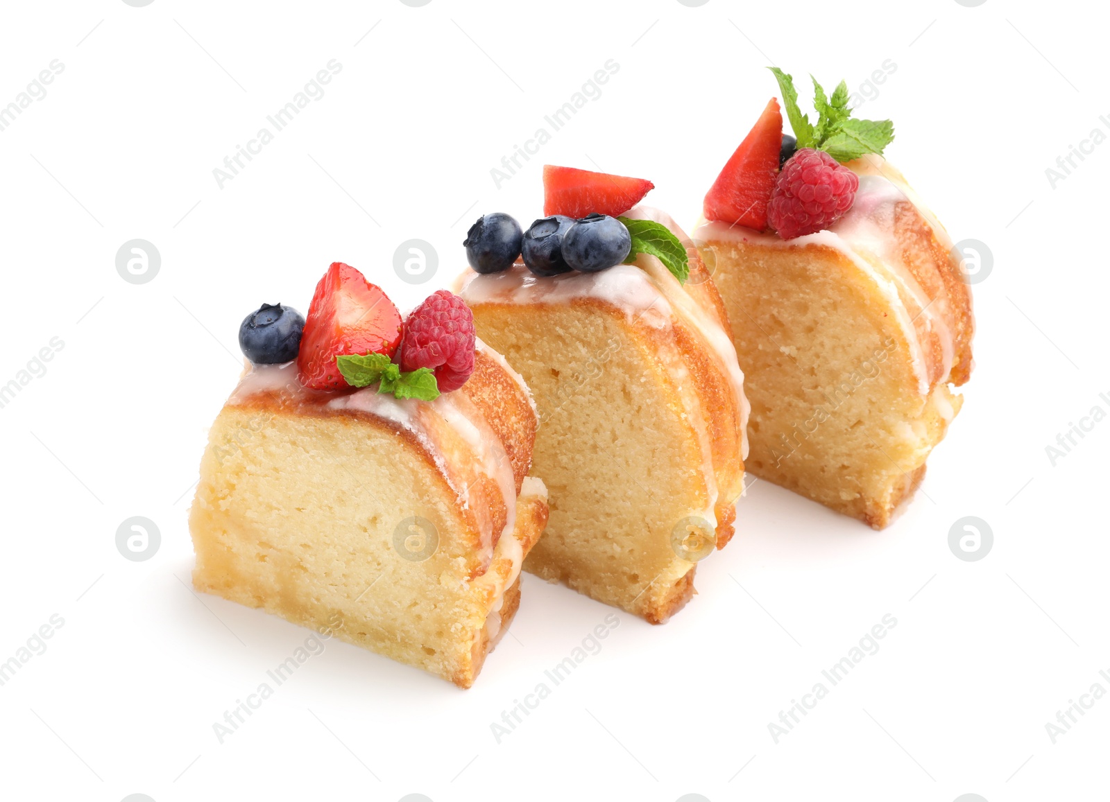 Photo of Pieces of delicious bundt cake with berries, glaze and mint isolated on white