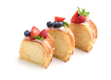 Photo of Pieces of delicious bundt cake with berries, glaze and mint isolated on white