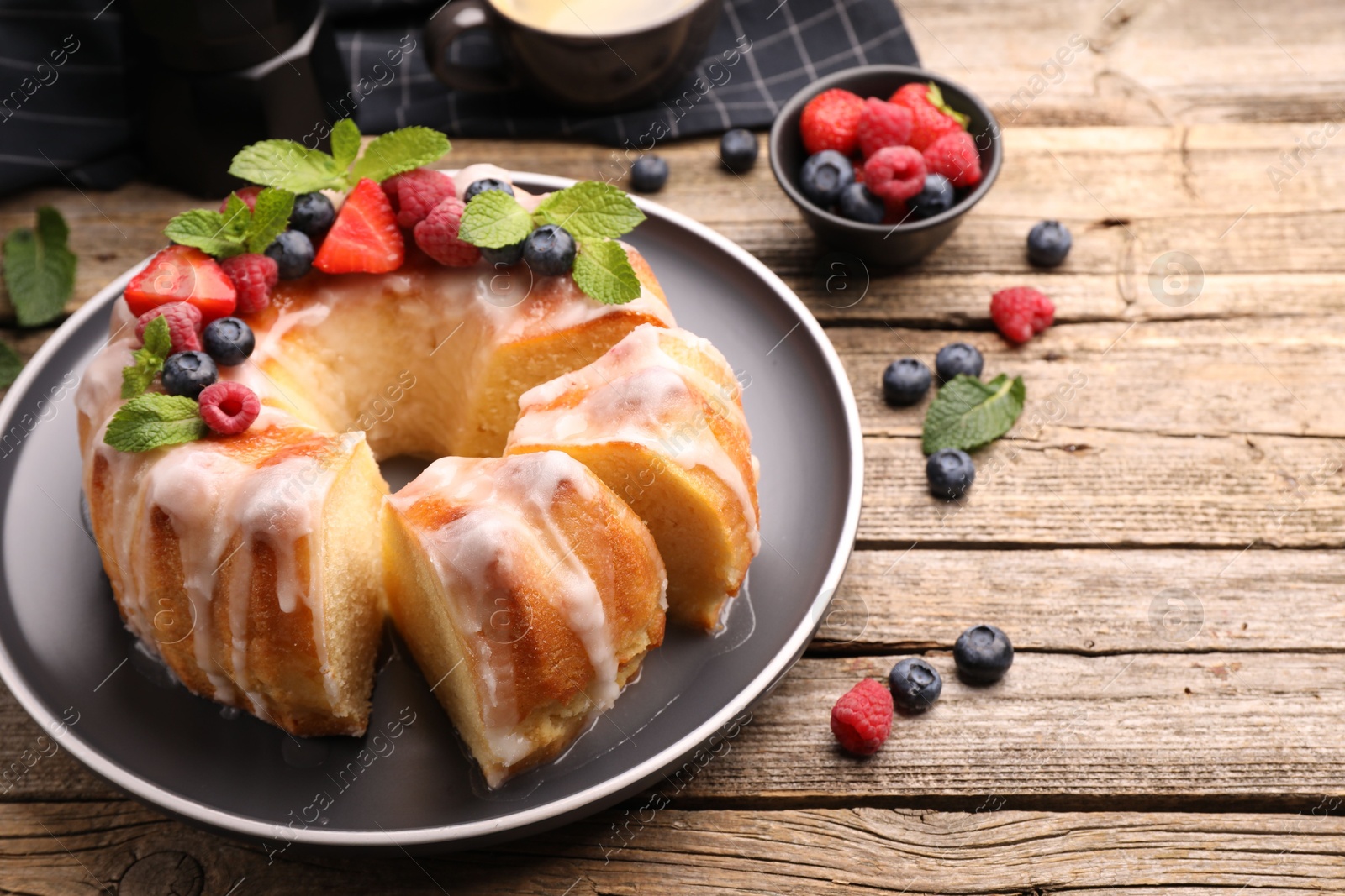 Pieces of delicious bundt cake with berries, glaze and mint on wooden table, closeup Photo of Pieces of delicious bundt cake with berries, glaze and mint on wooden table, closeup