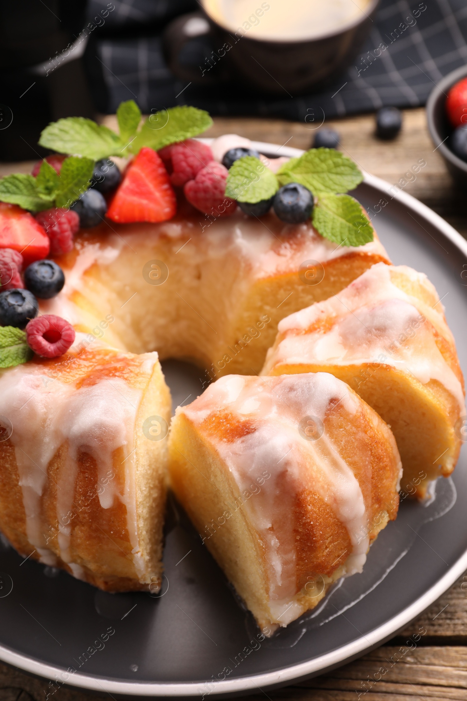 Pieces of delicious bundt cake with berries, glaze and mint on wooden table, closeup Photo of Pieces of delicious bundt cake with berries, glaze and mint on wooden table, closeup