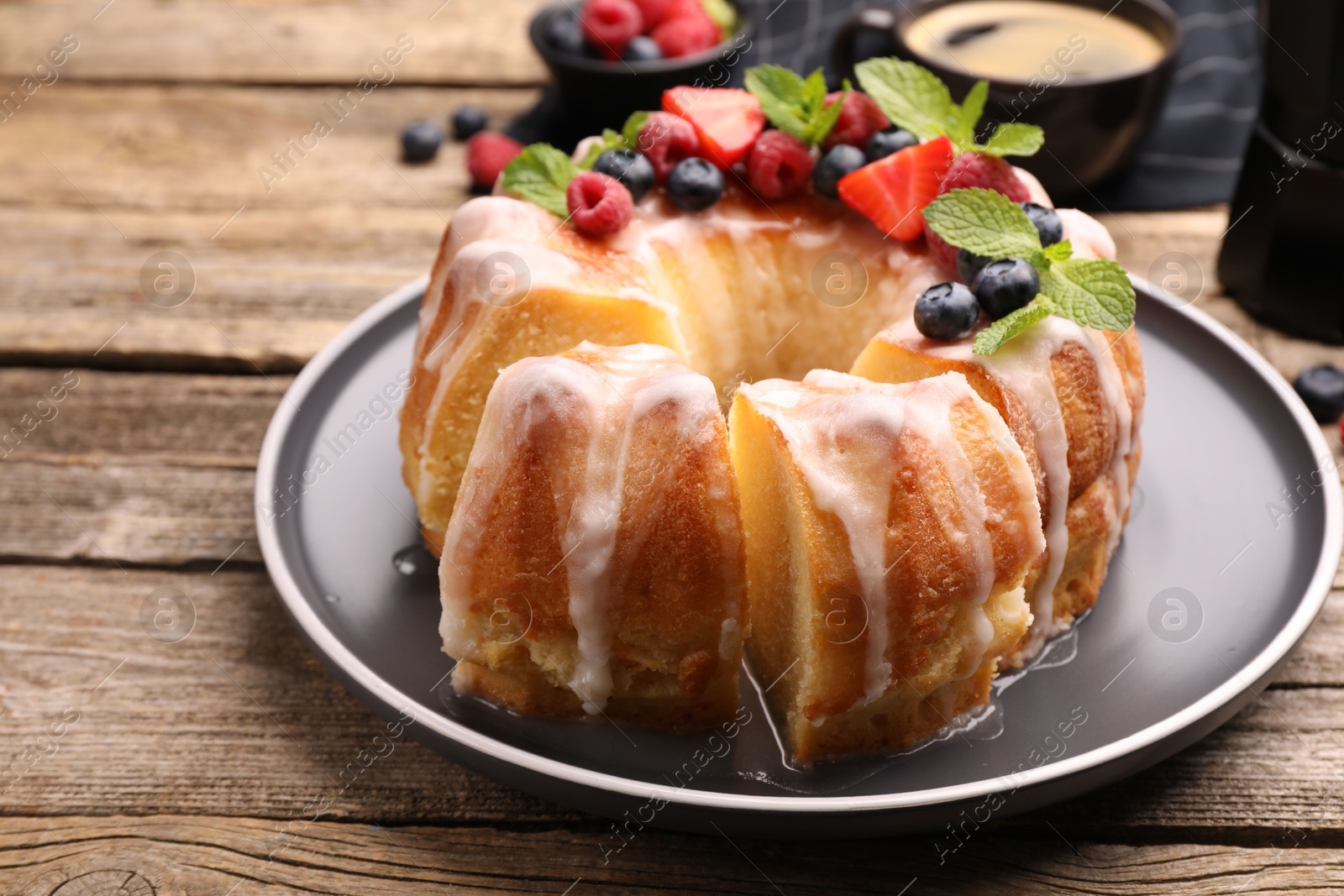 Pieces of delicious bundt cake with berries, glaze and mint on wooden table, closeup Photo of Pieces of delicious bundt cake with berries, glaze and mint on wooden table, closeup