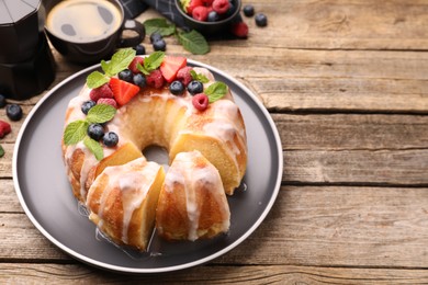 Photo of Pieces of delicious bundt cake with berries, glaze and mint on wooden table, closeup