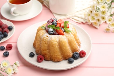 Photo of Delicious bundt cake with powdered sugar, berries and mint on pink wooden table, closeup