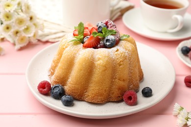 Photo of Delicious bundt cake with powdered sugar, berries and mint on pink wooden table, closeup