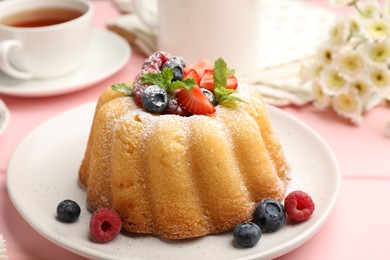 Photo of Delicious bundt cake with powdered sugar, berries and mint on pink wooden table, closeup