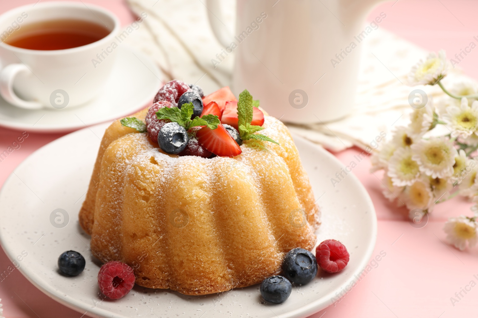 Photo of Delicious bundt cake with powdered sugar, berries and mint on pink wooden table, closeup