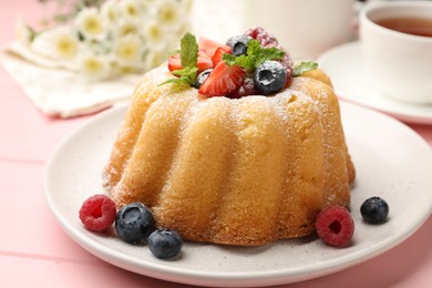 Photo of Delicious bundt cake with powdered sugar, berries and mint on pink wooden table, closeup