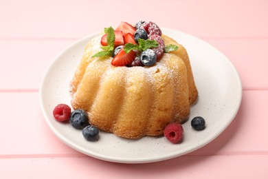 Photo of Delicious bundt cake with powdered sugar, berries and mint on pink wooden table, closeup