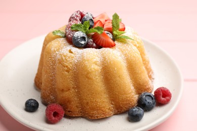 Photo of Delicious bundt cake with powdered sugar, berries and mint on pink table, closeup