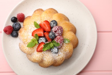 Photo of Delicious bundt cake with powdered sugar, berries and mint on pink wooden table, top view