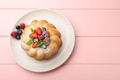 Photo of Delicious bundt cake with powdered sugar, berries and mint on pink wooden table, top view. Space for text