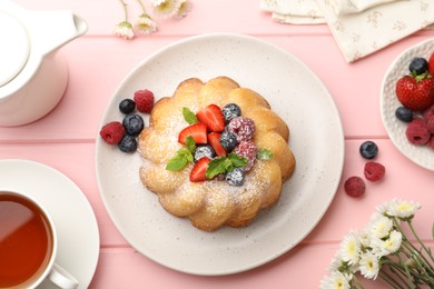 Photo of Delicious bundt cake with powdered sugar, berries and mint on pink wooden table, flat lay