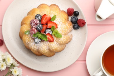 Photo of Delicious bundt cake with powdered sugar, berries and mint on pink wooden table, flat lay