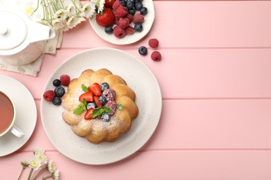 Photo of Delicious bundt cake with powdered sugar, berries and mint on pink wooden table, flat lay. Space for text