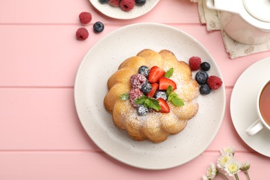 Photo of Delicious bundt cake with powdered sugar, berries and mint on pink wooden table, flat lay
